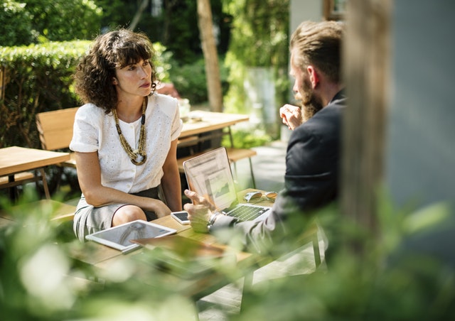 Two people sitting outside with laptop talking