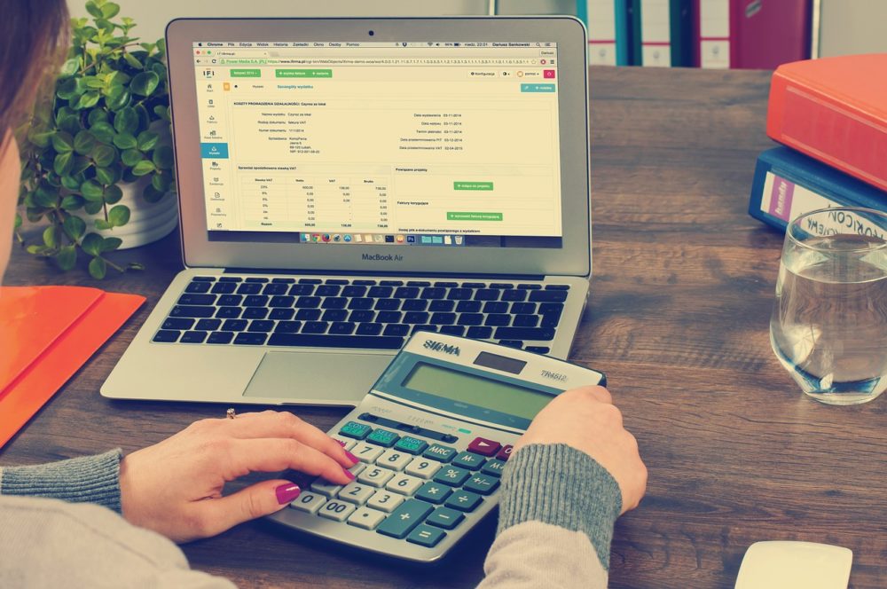 Desk of someone performing bookkeeping with laptop and calculator